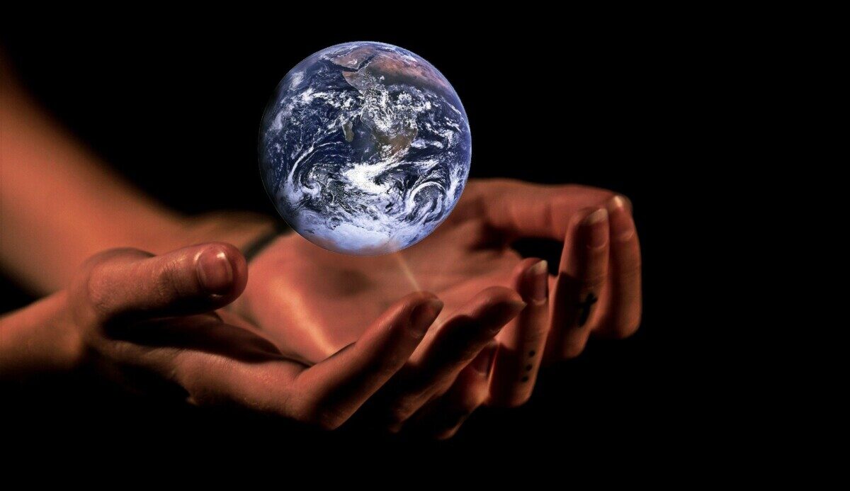 Der Planet Erde schwebt über zwei geöffneten Händen